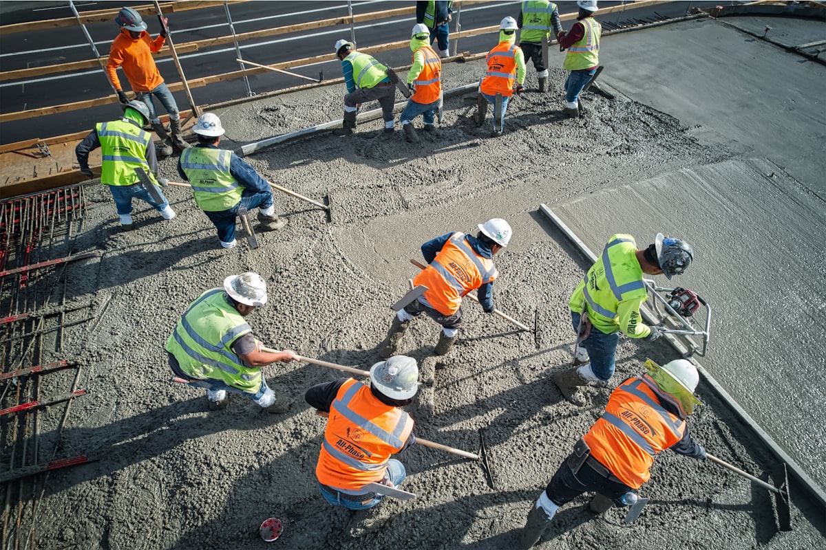 Concrete contractor pouring a foundation while wearing a branded work hat