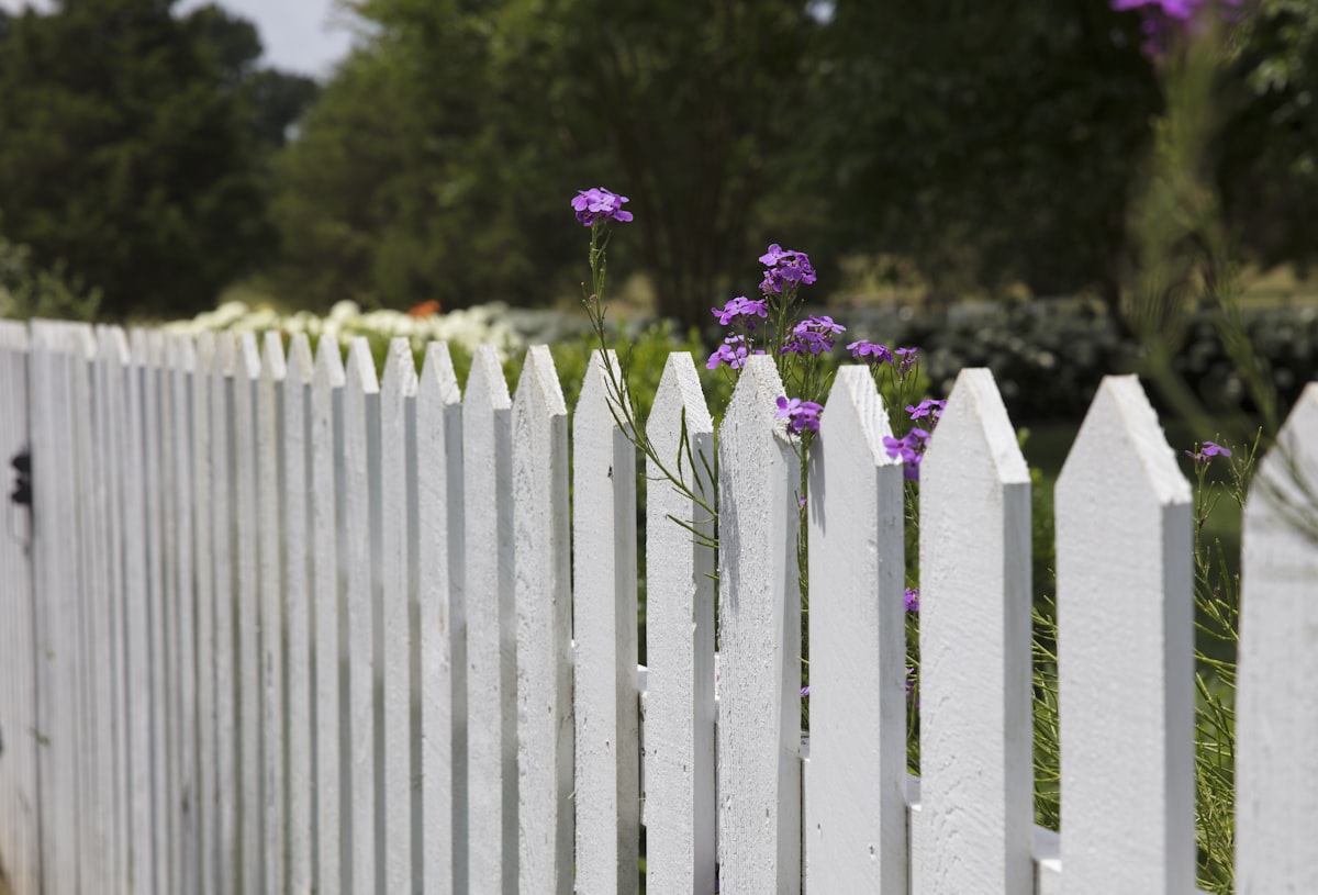 Fence company crew installing a wood privacy fence wearing branded hats